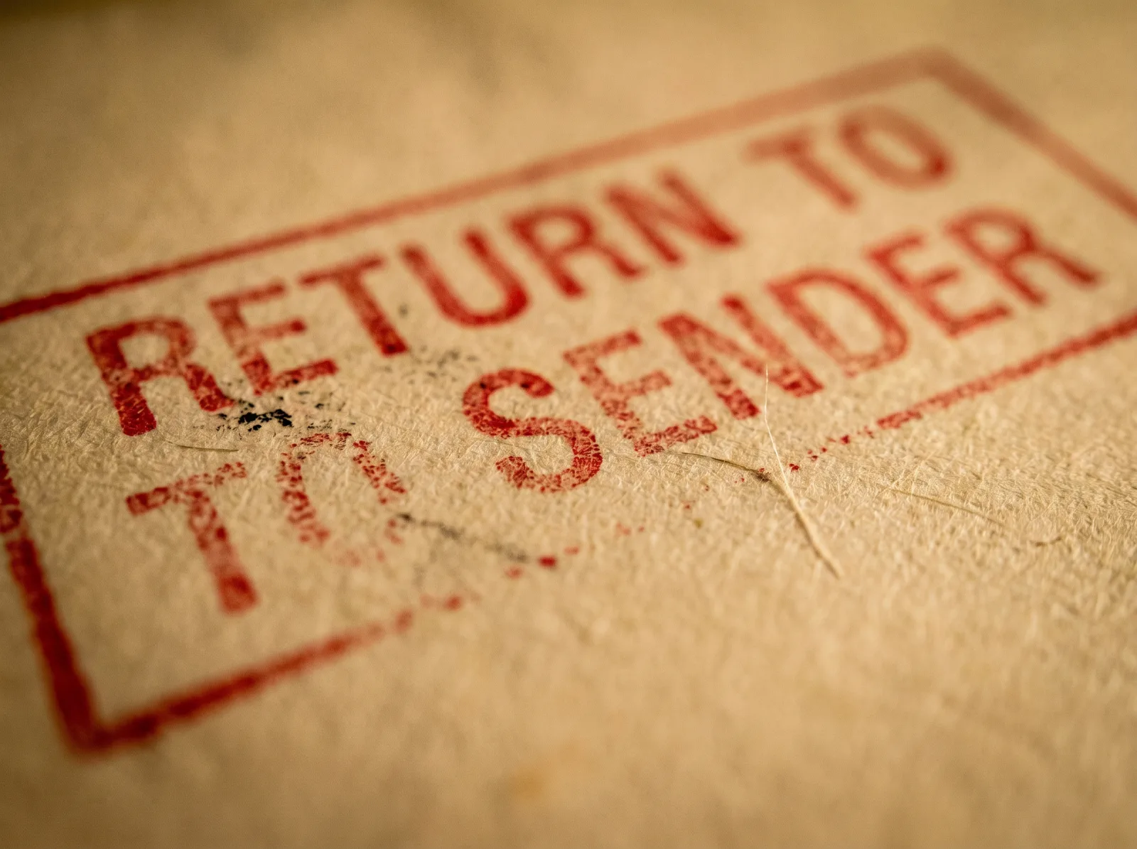 A red RETURN TO SENDER stamp struck twice across fibrous cream paper.